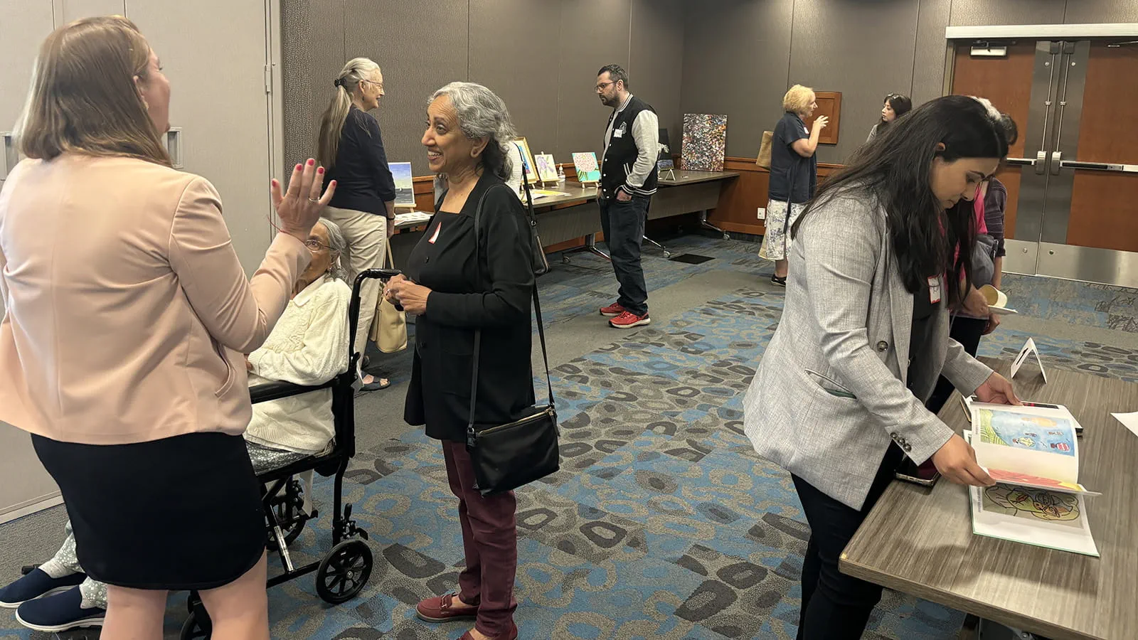 People talking and browsing artwork displayed on tables